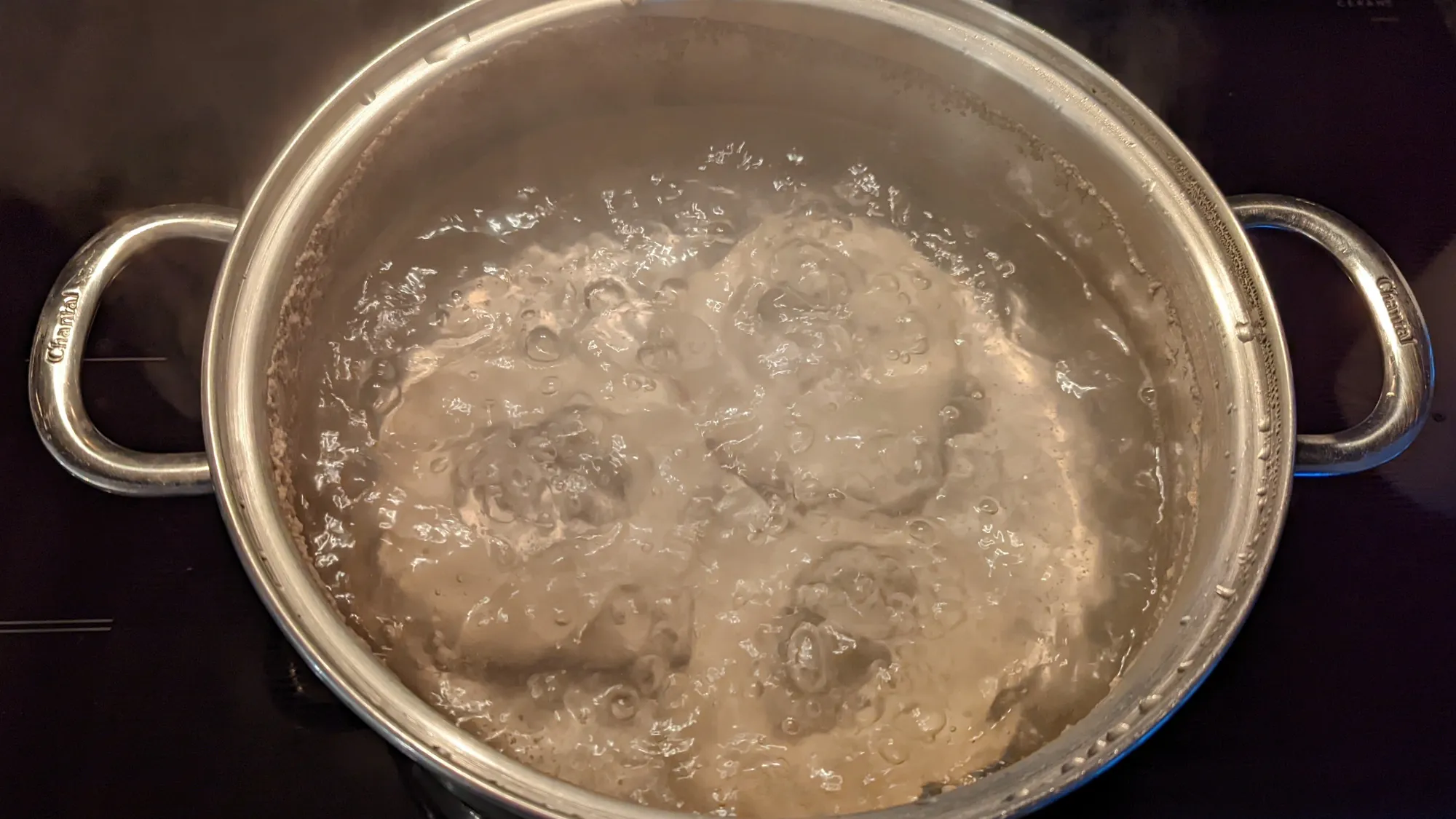 3 bagels simmering in a pot of brine.